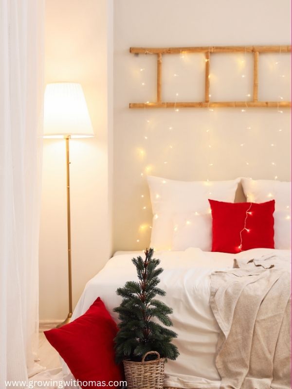 A-cozy-Christmas-bedroom-with-festive-pillows-blankets-lights-and-a-small-Christmas-tree