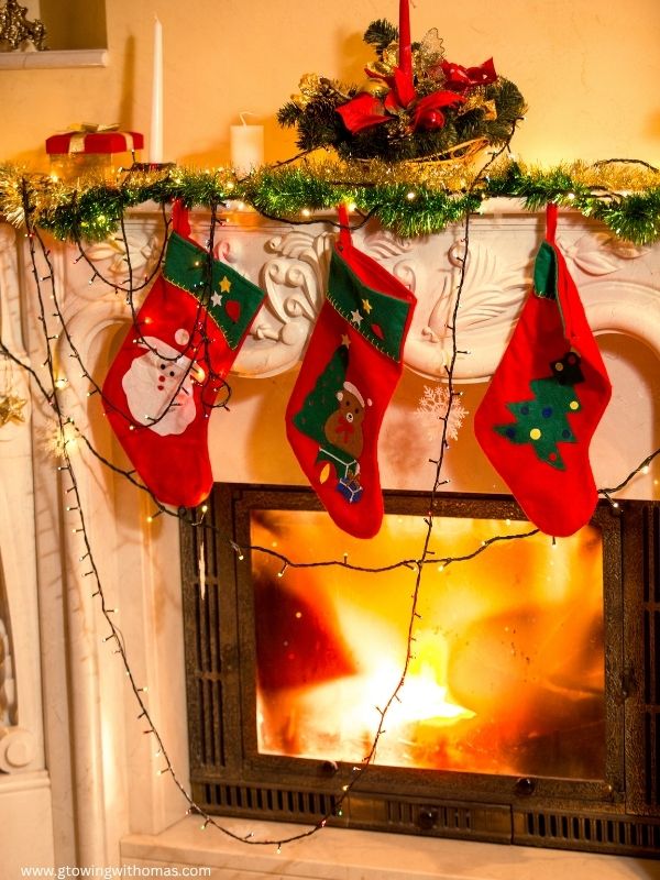 A-decorated-fireplace-mantel-with-Christmas-garland-stockings-candles-and-ornaments